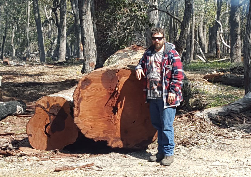 Ricki Malatesta with a log salvaged from a fenceline